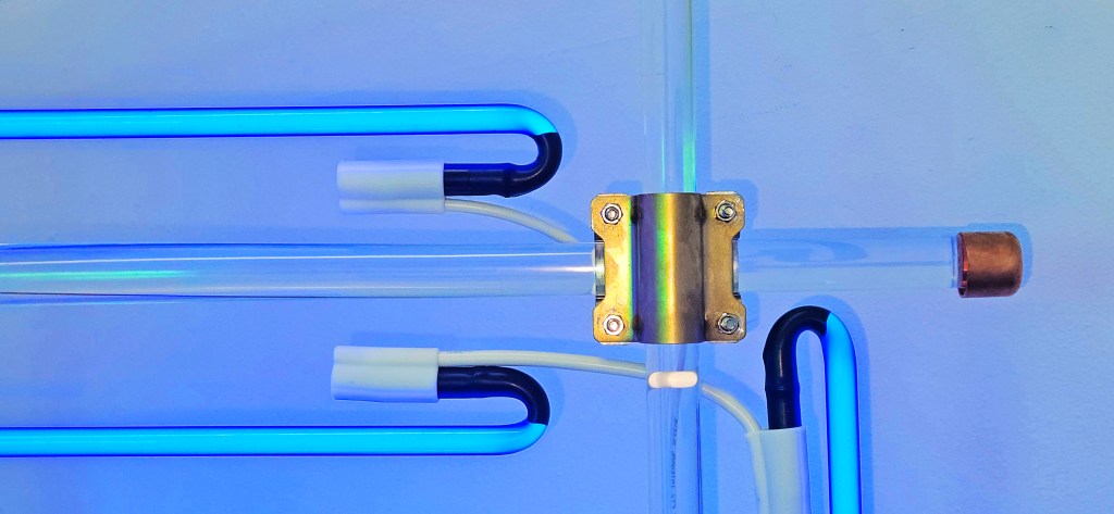 The Chiasm, is a Cobalt blue neon light and mirror sculpture installation with the semblance of a deconstructed manifestation of Constructivist Taitlin’s Tower. Senstad utilizes utilitarian, readymade materials, construction scaffolding aesthetics, and copper plumbing parts, reflecting the sacred in the ordinary. The installation acts as a portal within a confined space, a structural void.